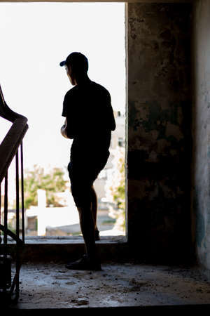 A person with depression is standing by the window at the entrance, wants to jumpの写真素材