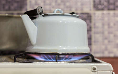 A stock photograph of a steaming stainless steel tea kettle on a flaming gas stove.の写真素材
