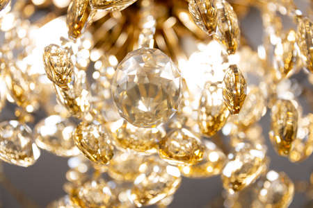 Close up on crystal of contemporary chandelier, is a branched ornamental light fixture designed to...