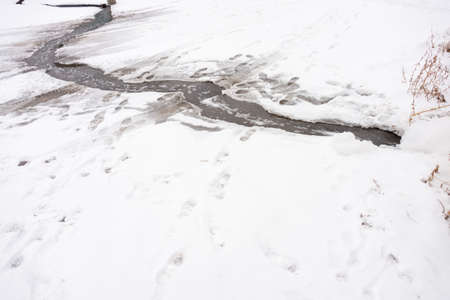 A detailed look at the water runs under the ice, the water from the tap flows into the streamの写真素材