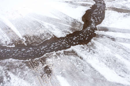 A detailed look at the water runs under the ice, the water from the tap flows into the streamの写真素材