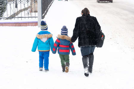 In winter, children with their mother return home from school.