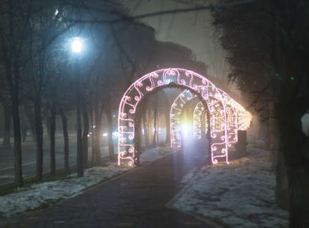 New Year's night city. The luminous arch is a Christmas decoration. Light tunnel with golden lights...