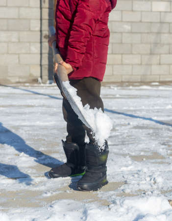 boy cleans snow in the yard with a shovelの写真素材