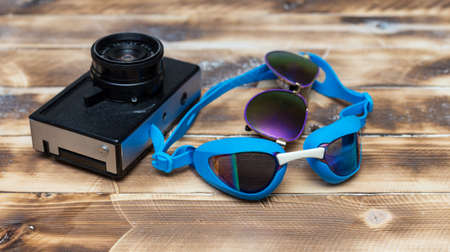 retro camera on a wooden table and swimming gogglesの写真素材