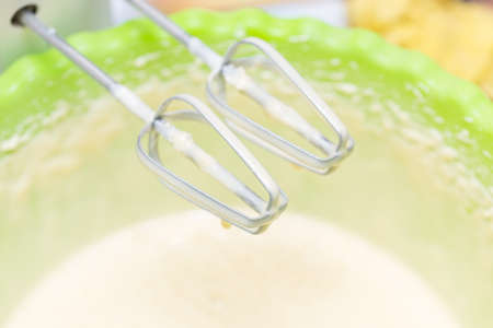 Mixing white egg cream in a bowl with a motor mixer, baking cake