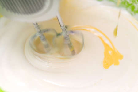 Mixing white egg cream in a bowl with a motor mixer, baking cakeの写真素材