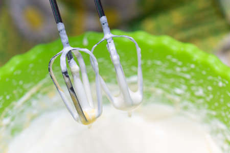 Mixing white egg cream in a bowl with a motor mixer, baking cakeの写真素材