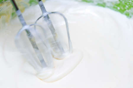 Mixing white egg cream in a bowl with a motor mixer, baking cakeの写真素材