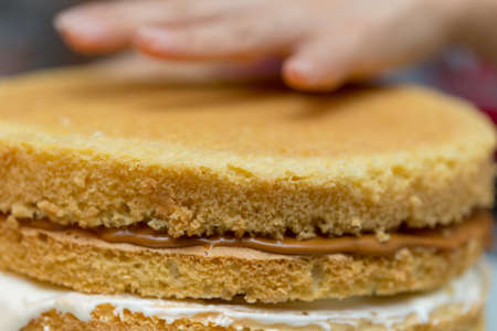 hand girl on a cake with milk chocolate cream. Macro shootingの写真素材
