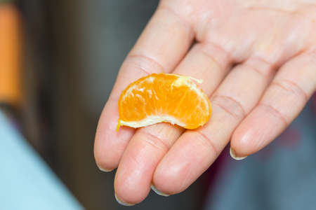 a piece of orange in handの写真素材