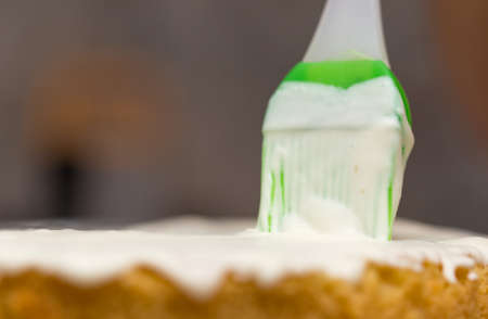 application of milk cream on the surface of the sweet cakeの写真素材