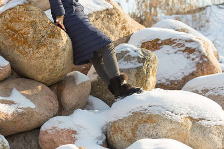beautiful girl is photographed against the backdrop of huge stones in the snow of different shapes and sizes, natural stone, winter backgroundの写真素材
