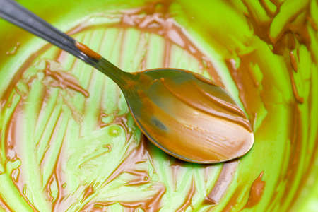 traces of remaining chocolate cream on the green mixture and steel spoonsの写真素材