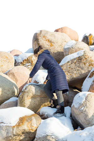 beautiful girl is photographed against the backdrop of huge stones in the snow of different shapes and sizes, natural stone, winter backgroundの写真素材