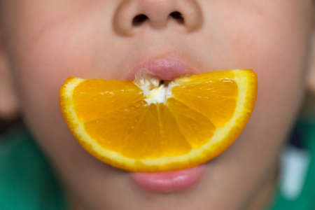 boy eating orange and lips smilingの写真素材