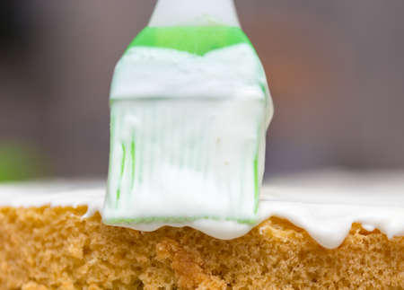 application of milk cream on the surface of the sweet cakeの写真素材