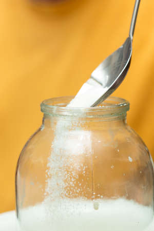 sugar poured into a jar with a steel spoon, close-upの写真素材