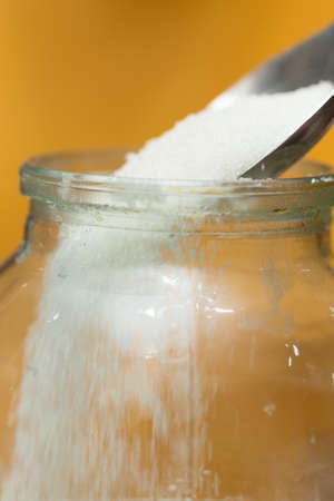 sugar poured into a jar with a steel spoon, close-upの写真素材