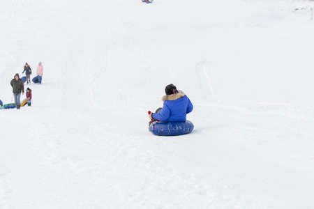 winter, leisure, sport, friendship and people concept - group of happy people sliding on the snow inflatable chambersの写真素材