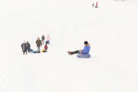 winter, leisure, sport, friendship and people concept - group of happy people sliding on the snow inflatable chambersの写真素材