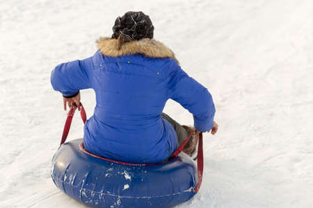 winter, leisure, sport, friendship and people concept - group of happy people sliding on the snow inflatable chambersの写真素材