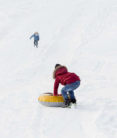 Brave child in red jackets, a trip in the winter from the mountains to tubing. He has an inflatable chamber. It slides quickly through the snow.の写真素材