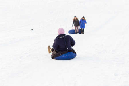 winter, leisure, sport, friendship and people concept - group of happy people sliding on the snow inflatable chambersの写真素材