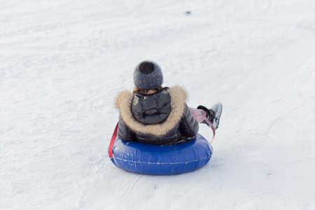 winter, leisure, sport, friendship and people concept - group of happy people sliding on the snow inflatable chambersの写真素材