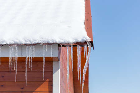 Icicles on vintage roof closeup. Winter weather concept. Froze and ice background. Christmas weather concept. Snow and icicle. Melting icicles. Long sharp icicles. Frozen water. Cold weather conceptの写真素材