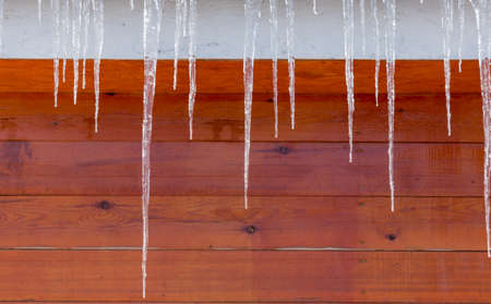 Icicles on vintage roof closeup. Winter weather concept. Froze and ice background. Christmas weather concept. Snow and icicle. Melting icicles. Long sharp icicles. Frozen water. Cold weather conceptの写真素材
