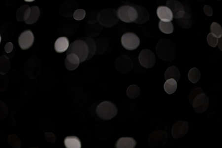 Snowstorm texture. Bokeh lights on black background, shot of flying snowflakes in the airの写真素材