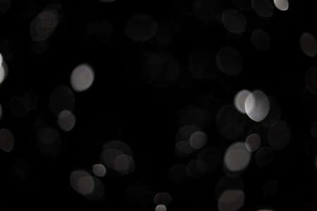 Snowstorm texture. Bokeh lights on black background, shot of flying snowflakes in the airの写真素材