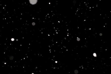 Snowstorm texture. Bokeh lights on black background, shot of flying snowflakes in the airの写真素材