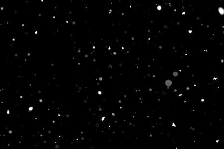 Snowstorm texture. Bokeh lights on black background, shot of flying snowflakes in the airの写真素材