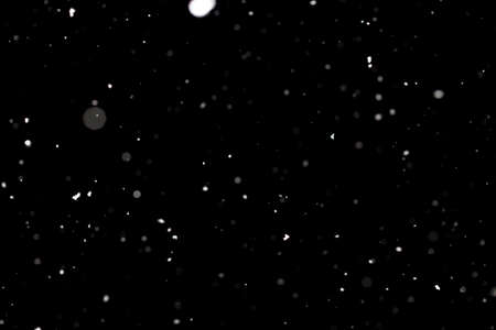 Snowstorm texture. Bokeh lights on black background, shot of flying snowflakes in the airの写真素材