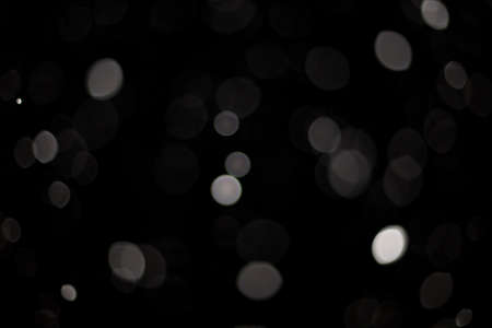 Snowstorm texture. Bokeh lights on black background, shot of flying snowflakes in the airの写真素材