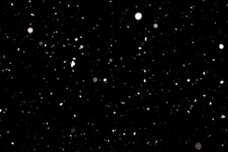 Snowstorm texture. Bokeh lights on black background, shot of flying snowflakes in the airの写真素材