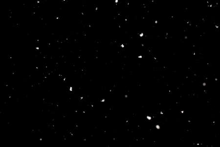 Snowstorm texture. Bokeh lights on black background, shot of flying snowflakes in the airの写真素材