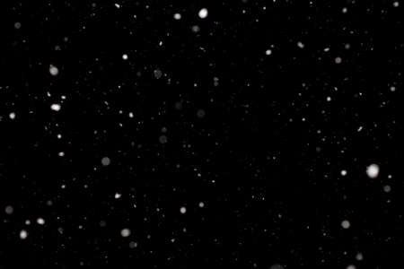 Snowstorm texture. Bokeh lights on black background, shot of flying snowflakes in the airの写真素材