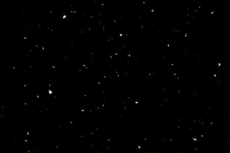 Snowstorm texture. Bokeh lights on black background, shot of flying snowflakes in the airの写真素材