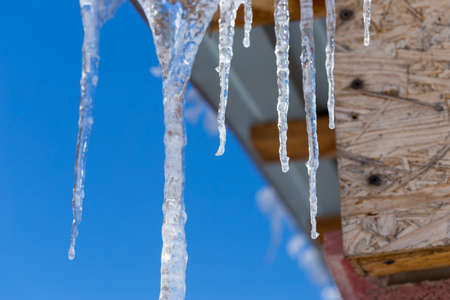Icicles on vintage roof closeup. Winter weather concept. Froze and ice background. Christmas weather concept. Snow and icicle. Melting icicles. Long sharp icicles. Frozen water. Cold weather conceptの写真素材