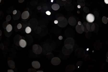 Snowstorm texture. Bokeh lights on black background, shot of flying snowflakes in the airの写真素材