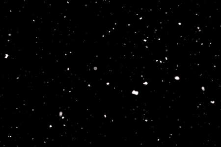 Snowstorm texture. Bokeh lights on black background, shot of flying snowflakes in the airの写真素材