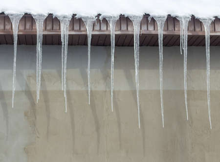 Icicles on vintage roof closeup. Winter weather concept. Froze and ice background. Christmas weather concept. Snow and icicle. Melting icicles. Long sharp icicles. Frozen water. Cold weather conceptの写真素材