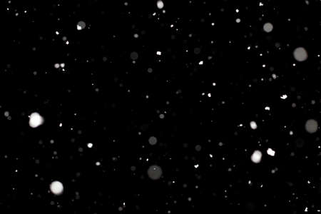 Snowstorm texture. Bokeh lights on black background, shot of flying snowflakes in the airの写真素材