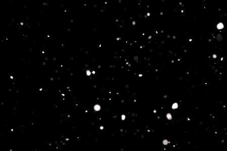 Snowstorm texture. Bokeh lights on black background, shot of flying snowflakes in the airの写真素材