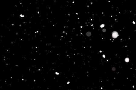 Snowstorm texture. Bokeh lights on black background, shot of flying snowflakes in the airの写真素材