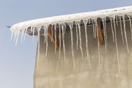 Icicles on vintage roof closeup. Winter weather concept. Froze and ice background. Christmas weather concept. Snow and icicle. Melting icicles. Long sharp icicles. Frozen water. Cold weather conceptの写真素材