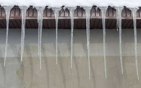 Icicles on vintage roof closeup. Winter weather concept. Froze and ice background. Christmas weather concept. Snow and icicle. Melting icicles. Long sharp icicles. Frozen water. Cold weather conceptの写真素材